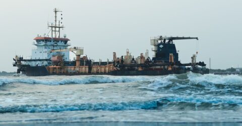Large cargo ship navigating rough ocean waters showing structural steel joints